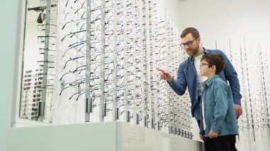 Little boy in optics store choosing glasses with his father. Ophthalmology concept.