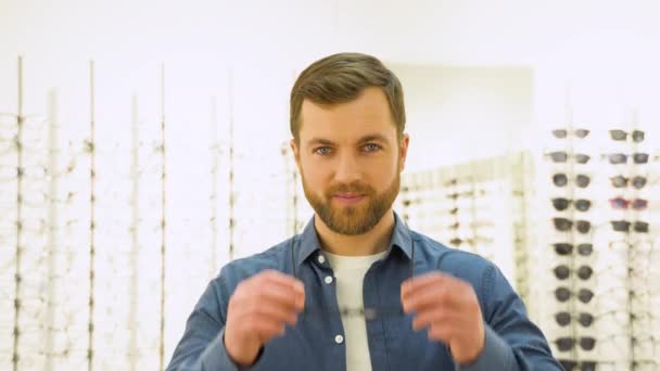 Happy Young Male Client Puts New Glasses Rack Showcase Eyewear — Vídeo de Stock
