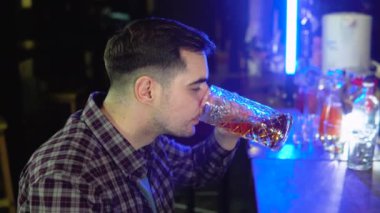 Portrait of a handsome caucasian young man drinking tasty golden refreshing beer beverage in a pub.