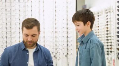 Little boy in optics store choosing glasses with his father. Ophthalmology concept.