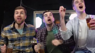 Loyal football fans supporting their team. Men cheering their team in the pub.