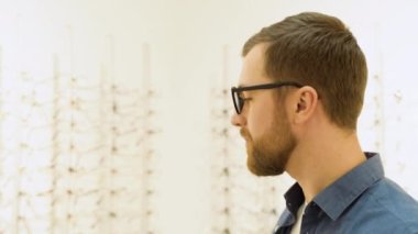 Happy young excited male customer surprised by a large selection of glasses at optics store.