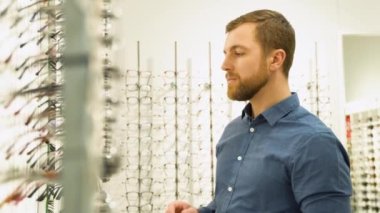 Health care, eyesight and vision concept - a man choosing glasses at optics store.