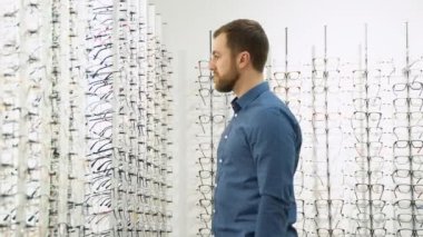Health care, eyesight and vision concept - a man choosing glasses at optics store.