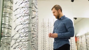Health care, eyesight and vision concept - a man choosing glasses at optics store