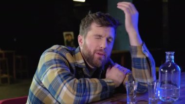 A man sitting at a bar drinking shots or vodka. Drinking, going out, inclusivity and alcohol concept.