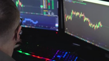 Monitörün yanında oturan mutlu borsacı elinde finans piyasası grafiğindeki kripto para bilgileri var. Başarılı bir ticareti kutlayan tüccar..