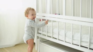 Baby taking first steps near the bed