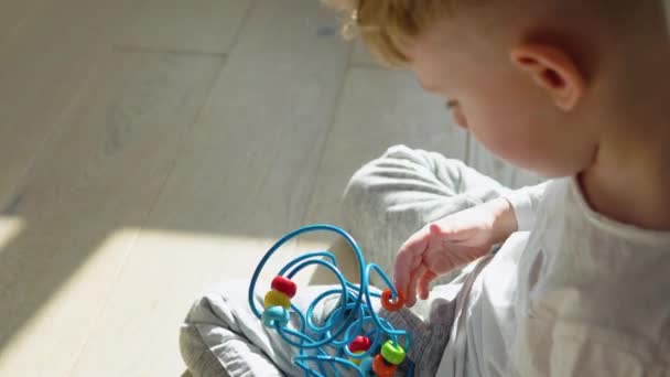 小さな男の子は保育園で床の上で教育の論理的なおもちゃを果たしている — ストック動画