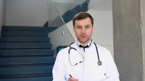 Uśmiechnięty Młody Kaukaski Lekarz Białym Mundurze Medycznym Wykazuje Dobrą Jakość — Wideo stockowe