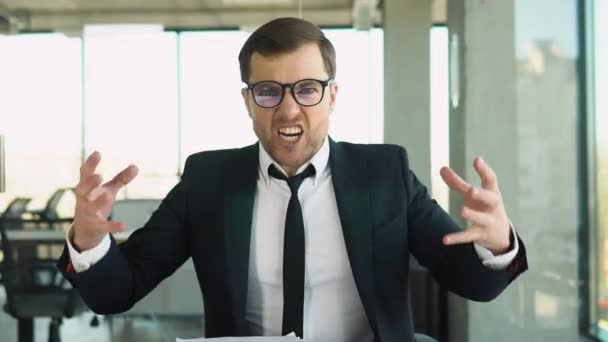 怒っている上司は従業員にカメラで叫ぶ彼の指を側に向ける部下を解雇し ビジネススーツのビジネスマンは現代のオフィスのテーブルに座っている — ストック動画