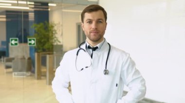 Beyaz tıp üniformalı, gülümseyen beyaz erkek doktor hastanede iyi hizmet veriyor. Klinikteki mutlu pratisyen hekimin ya da çocuk doktorunun portresi. Sağlık hizmetleri kavramı.
