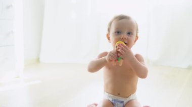 Cute child in diaper playing on the floor in nursery