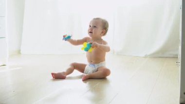 Cute child in diaper playing on the floor in nursery