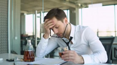 Young businessman drinking from stress at workplace.