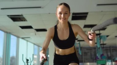 Strong woman exercising with battle ropes at the gym with male trainer. Athlete doing battle rope workout at gym with instructor.