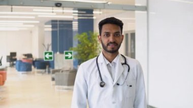 Happy young indian male doctor shows thumbs up sign.