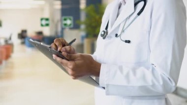 Doctor writes notes or prescription on clipboard