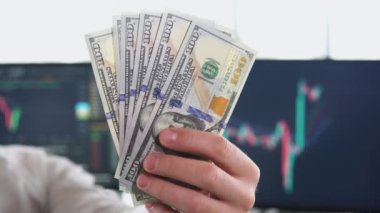Dolar taşıyan iş elbiseli bir adam. Nakit para elinde. Kâr, tasarruf. Yığınla dolar. Adam para sayıyor. Dolarlar erkeklerin elinde. Başarı, motivasyon, finansal akışlar, zenginlik. Yığınla dolar.
