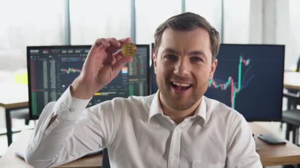 Zadowolony Człowiek Trzyma Złotą Monetę Ręku Tle Wykresów Finansowych — Wideo stockowe