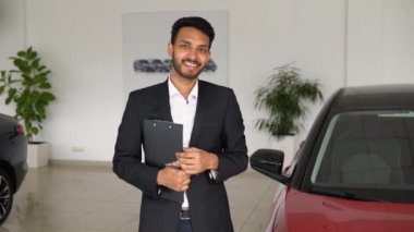 Portrait of a successful indian male manager in a car dealership, car sales.