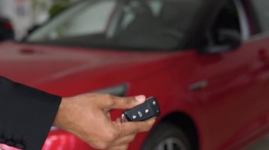 Indian car manager giving keys to customer at salon. Two men shaking hands for making deal. Close up of hands, blur background. Concept of car selling
