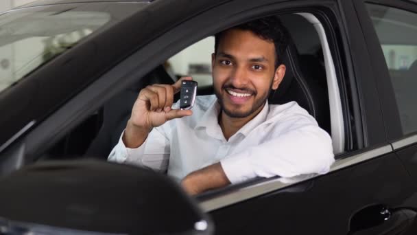 快乐的印度人坐在新汽车商店的经销店里庆祝新汽车的购买 开新车的时候 那个拿着钥匙的人表现出一副喜庆的样子 — 图库视频影像