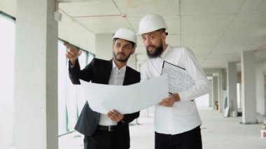 Hintli mimar ve Arap yönetici inşaat alanında buluşuyorlar. Çok ırklı işçi ve mühendis plan üzerinde tartışıyorlar. Yeni bir binayı ziyaret ederken birlikte çalışan iki inşaat işçisi.
