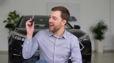 Anahtarı olan mutlu adam bir araba galerisinden yeni bir elektrikli araba almaktan memnun.