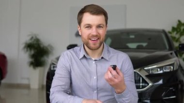 Anahtarı olan mutlu adam bir araba galerisinden yeni bir araba almaktan memnun..