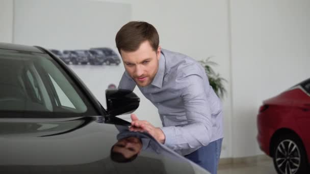 一个英俊的男人在展示室里摸一辆新的黑色汽车的画像 有信心的年轻白种人买主羡慕汽车经销店里的汽车 生活方式和成功概念 — 图库视频影像