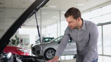 Satın almadan önce açık kaputlu aracı inceleyen bir adam