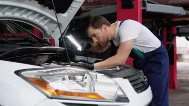 Araba Servisi, tamir, bakım ve insan kavramı - otomatik mekanik adam atölyesinde çalışan lambalı.