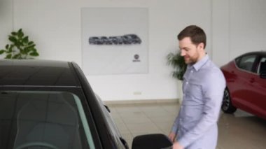 Yeni lüks bir arabanın yanındaki galeride duran mutlu adam. Satın almak için aracı seçen yakışıklı bir genç. Otomatik iş kavramı
