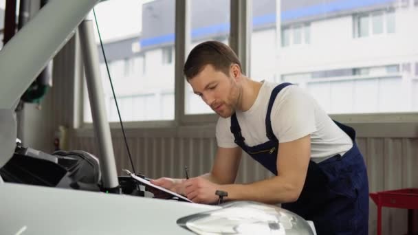 汽车修理工检查汽车发动机并在剪贴板上书写 汽车维修服务概念 — 图库视频影像