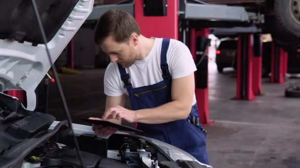 Profesjonalny Mechanik Samochodowy Pracujący Serwisie Samochodowym Tabletem Dorosły Mężczyzna Mundurze — Wideo stockowe