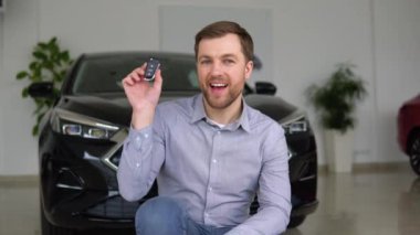 Anahtarı olan mutlu adam bir araba galerisinden yeni bir araba almaktan memnun.