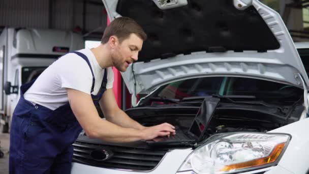 专业汽车修理工用笔记本电脑从事汽车维修服务 在汽车沙龙工作的穿制服的成年人 — 图库视频影像
