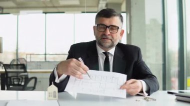Gülümseyen bir emlakçı ev tasarımı seçeneklerini gösterir ve sunar