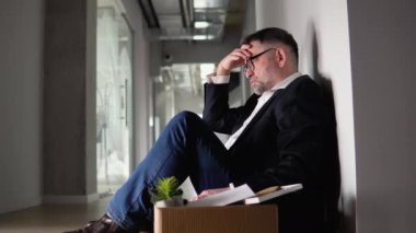 Ofisin yanındaki koridorda sinirli ve sinirli bir şekilde oturan kıdemli çalışanı işten çıkarma kutusuyla kovdu ve alkol içti. İşini ya da emekliliğini kaybetti..