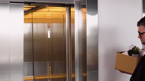 サッドはシニア労働者を解雇したカートンの解雇箱でエレベーターに入った 老人は引退している 引退のコンセプト 仕事からの解雇 — ストック動画