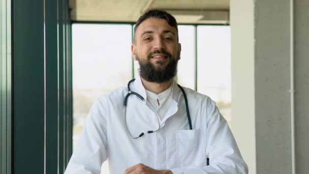 白い医療制服を着た若いアラビア人男性医師の笑顔は 病院で良い品質のサービスを示しています 病院で幸せな男のGpや小児科医のヘッドショットの肖像画 医療の概念 — ストック動画