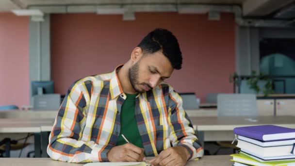 Готовлюсь Экзаменам Задумчивый Молодой Индийский Студент Пишет Блокноте Читает Книгу — стоковое видео