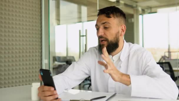 病院のオフィスデスクに座ってタブレット画面上のオンライン患者を迎える統一されたアラビア語の医師 オンライン相談サービス 病気の人のための遠隔医療アプリケーション — ストック動画