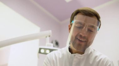Ameliyathanedeki erkek cerrah hastaya bakıyor.