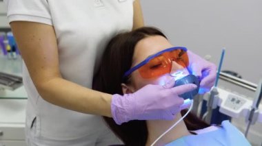 Ultraviyole lambalı diş beyazlatma prosedürü. Klinikteki dişçide çalışan bir kadının yakın plan portresi..