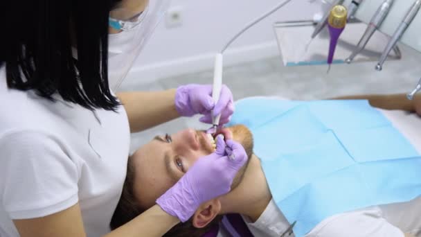 Dentystka Masce Okularach Robi Zabieg Dla Męskiego Pacjenta Trzyma Narzędzia — Wideo stockowe