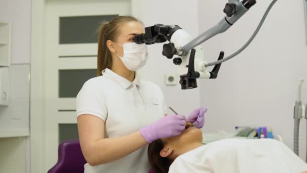 Dentystka Badająca Młodą Dziewczynę Patrzącą Zęby Profesjonalnym Mikroskopem Gabinecie Stomatologicznym — Wideo stockowe