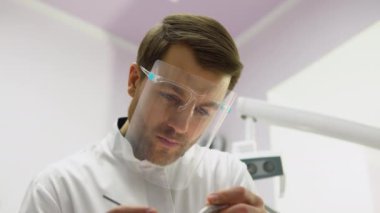Diş hekiminin portresi diş aletlerini tutar ve dişleri tedavi eder. Diş hekimliğinde ağız sağlığı ve diş tedavisi. Stomatoloji kliniğinde stomatolog.