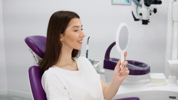 歯医者のオフィスで笑顔で鏡を見て美しい若い女性 私の笑顔は完璧です — ストック動画